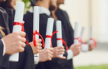 Graduados con sus diplomas enroscados en las manos.