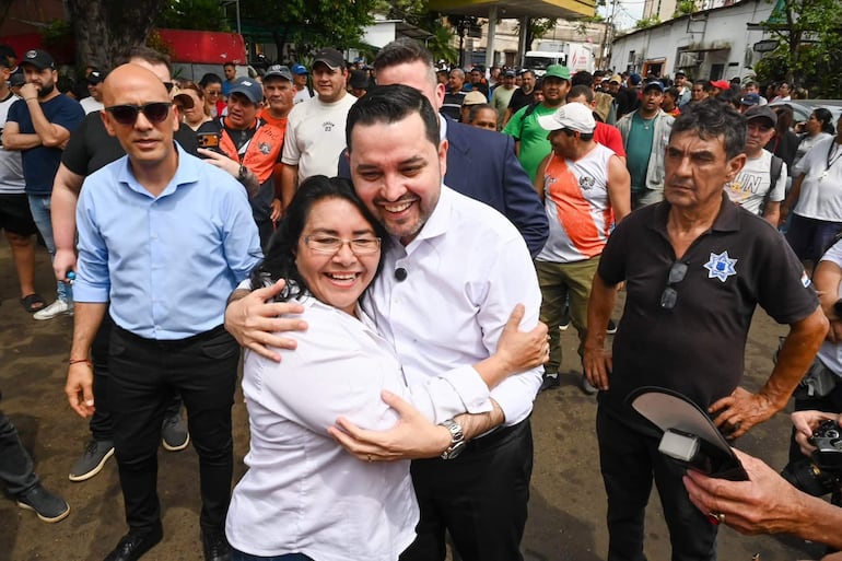 Luis Bello y José Gregorio Ledesma Narvaez abrazados, ambos sonrientes, rodeados de una multitud en un entorno urbano.