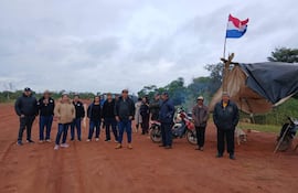 Grupo de personas en carpa de resistencia, con bandera de Paraguay al fondo y algunos motocicletas estacionadas.