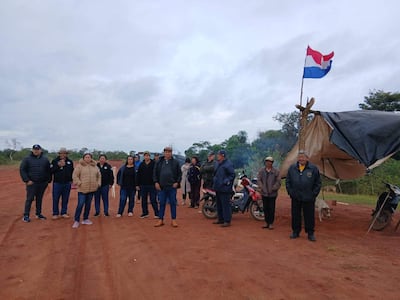 Grupo de personas en carpa de resistencia, con bandera de Paraguay al fondo y algunos motocicletas estacionadas.