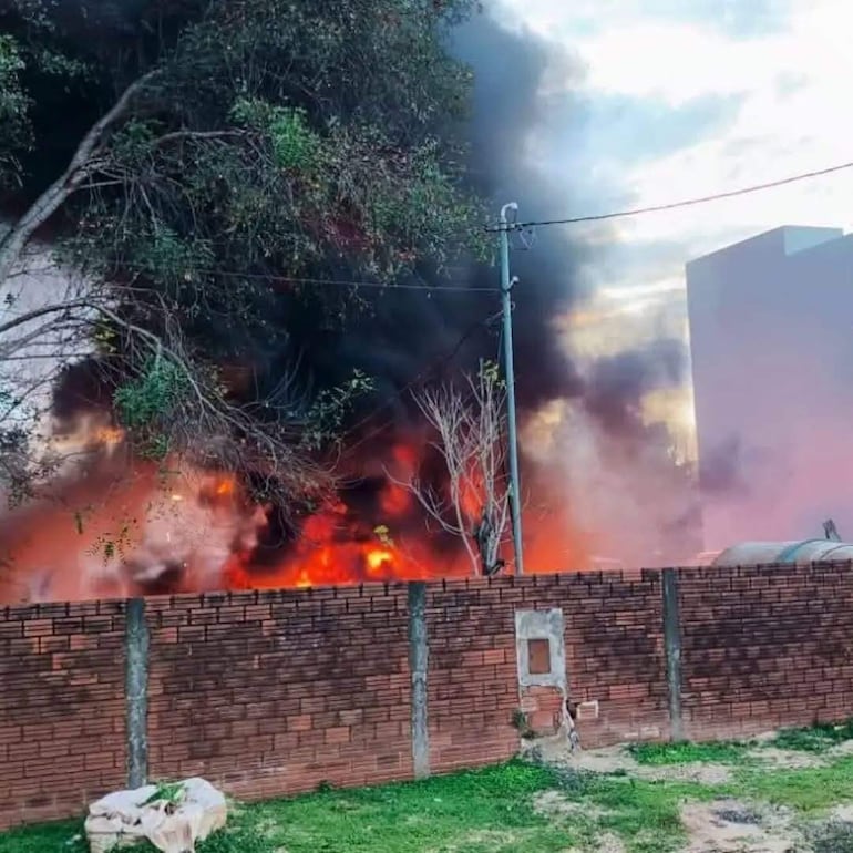 Columna densa de humo negro se eleva sobre el fuego en el barrio Mboika'e, con llamas naranjas y rojas visibles en el incendio.