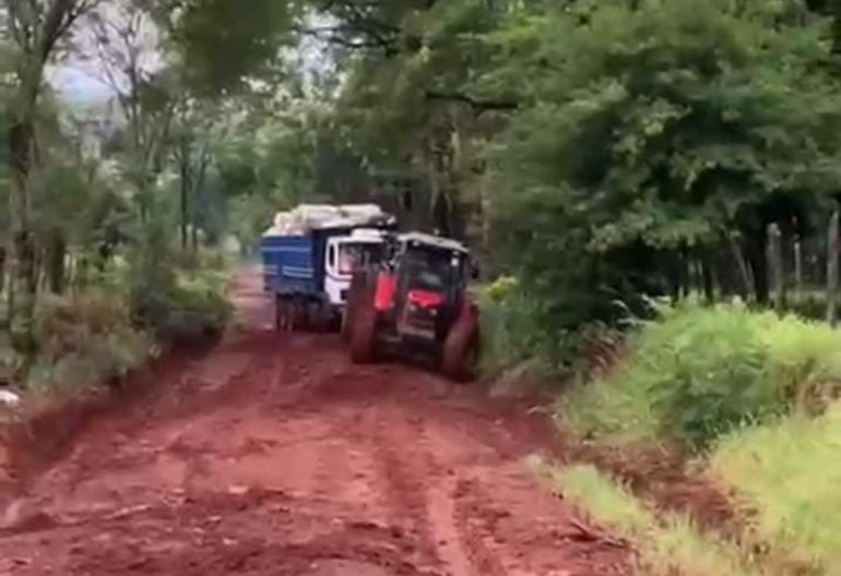 Un tractor agrícola trata de sacar de un charco a un camión cargado de bolsas de choclos en la zona de la colonia Primavera Real