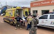 Grupo de personas ayuda a un rehén en camilla mientras un bombero y un policía observan la situación en un entorno urbano.