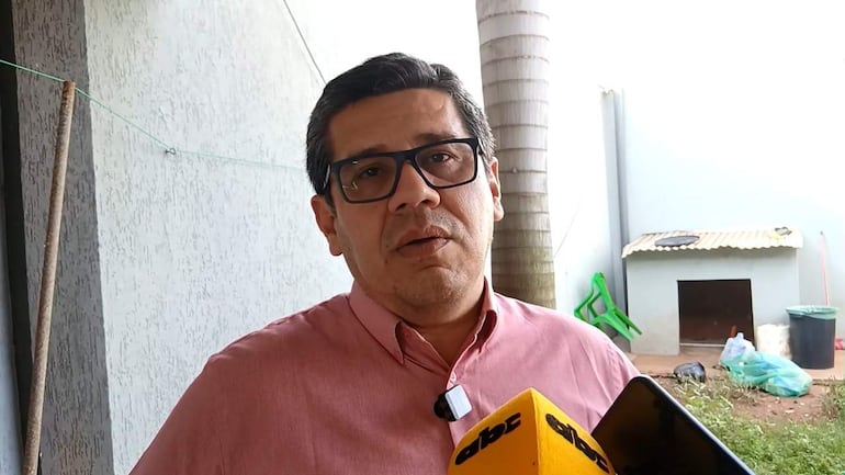 Hombre en camisa rosa con gafas sostiene un micrófono amarillo de ABC Color en un entorno al aire libre.