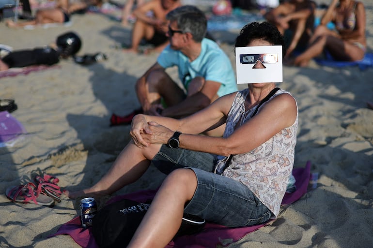 Personas observan el eclipse solar total desde la playa de La Zurriola, en San Sebastián, el 12 de agosto de 2026.