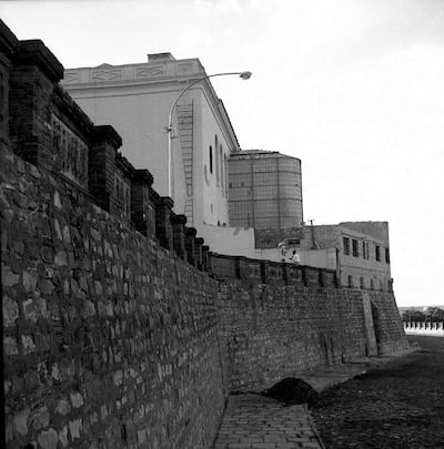 Vista de una fortificación de ladrillo y un edificio histórico, ambos en blanco y negro, sin presencia humana.