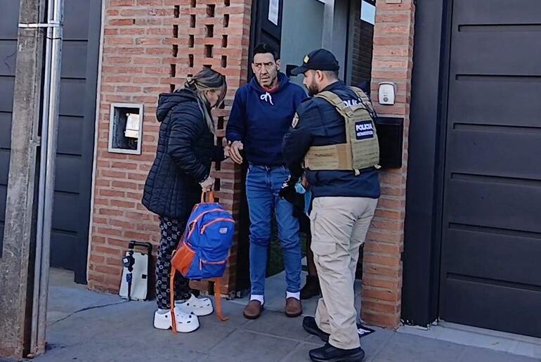Narciso Ayala con camisa azul y pantalones claros es entrevistado por un oficial de policía en un ambiente urbano.