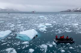 La bióloga de la Cornell University de Nueva York sumerge un hidrófono cubierto de titanio y atado a una boya, en medio del imponente océano coronado por témpanos de hielo, en el archipiélago de las Islas Shetland del Sur.