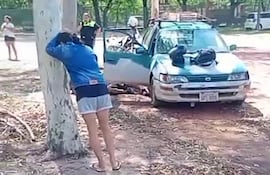 La pareja de Ever Hugo Ayala llorando recostada a un árbol. El conductor murió tras una retención de la PMT de Asunción y los familiares denuncian pago de coima.