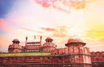 Vista exterior de la Puerta de la Ciudad Roja con bandera india ondeando y cielo en tonos cálidos.