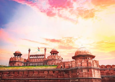 Vista exterior de la Puerta de la Ciudad Roja con bandera india ondeando y cielo en tonos cálidos.