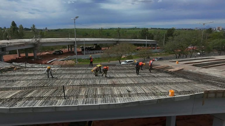 Seis trabajadores en construcción con cascos, manipulando materiales y maquinaria en un día nublado.