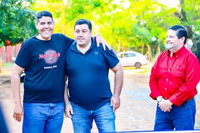 Baeza sonríe con camiseta negra, Romero escucha con expresión neutral, y Servín también sonríe con camisa roja en un entorno natural.