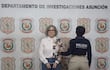 Rosa Colmán, de cabello rizado y canoso, vestida con camisa blanca y jeans, es sostenida por una mujer policía.
