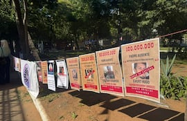 Carteles en un parque sobre deudores alimentarios, con textos en guaraní. Sin personas visibles en la imagen.