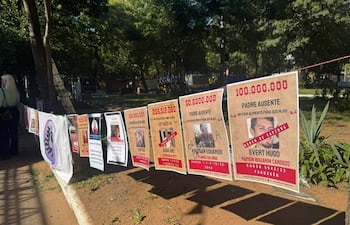 Carteles en un parque sobre deudores alimentarios, con textos en guaraní. Sin personas visibles en la imagen.
