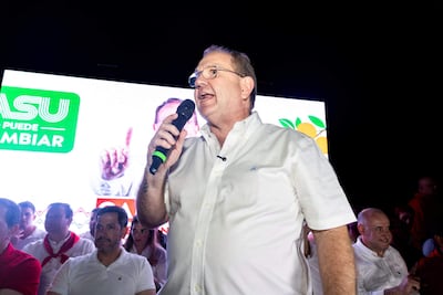 Raúl Latorre Martínez habla con entusiasmo al público, rodeado de personas vestidas principalmente con camisas blancas y rojas.