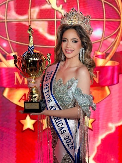 Mujer sonriente con un vestido brillante y corona, sosteniendo un trofeo y un segundo premio en un evento de premiación.
