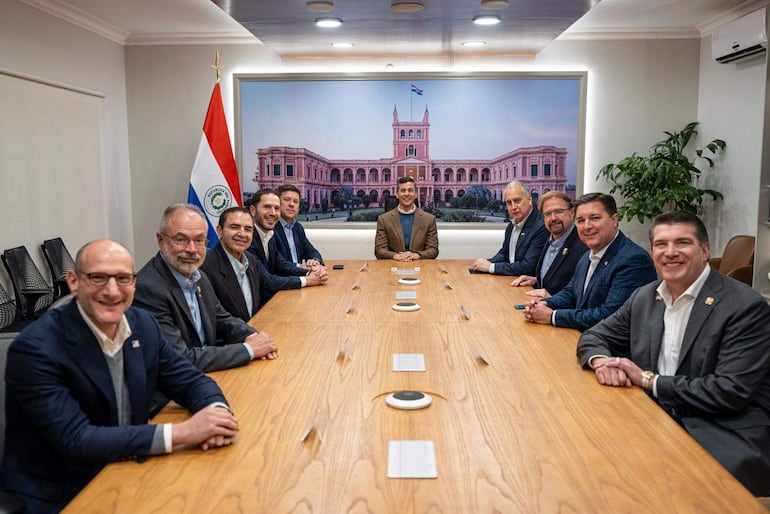 Santiago Peña en mesa de reuniones con congresistas estadounidenses, todos vestidos formalmente y conversando en ambiente institucional.