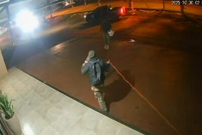 Uno de los asaltantes extiende el cordón detonante alrededor del edificio del banco Itaú de Katueté.