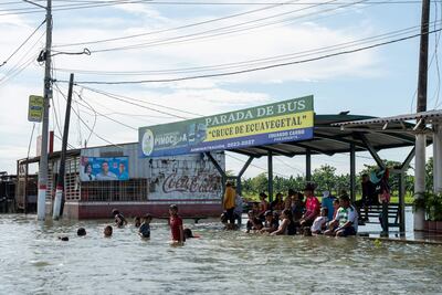 Personas esperan en una zona inundada en Babahoyo, provincia de Los Ríos (Ecuador).