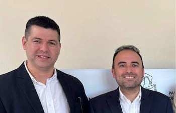 Jorge Bogarín Alfonso y Emilio Acevedo sonrientes, vestidos con trajes formales, en un ambiente interior.