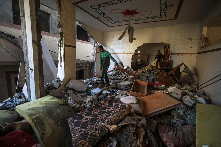 Dos hombres revisan los escombros de una casa dañada por un bombardeo israelí, el pasado jueves en Deir el Balah.