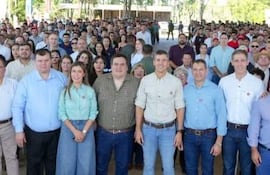 Dionisio Amarilla y Santiago Peña sonriendo en un acto al aire libre, rodeados de árboles y asistentes alegres.