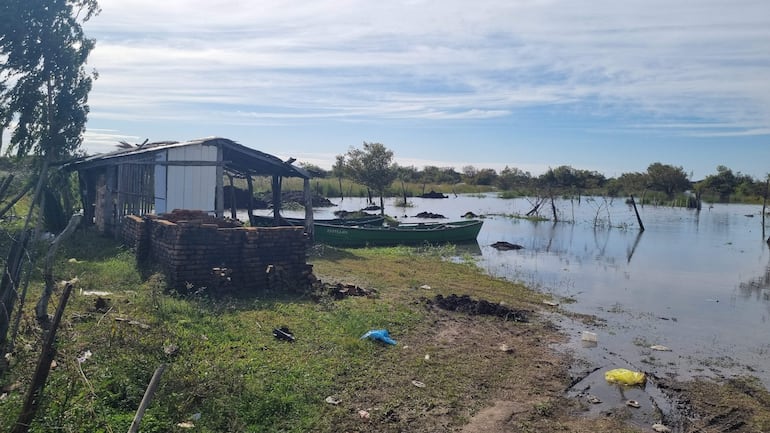 Paisaje inundado en Villa Florida con refugio deteriorado y bote verde flotando en el agua.