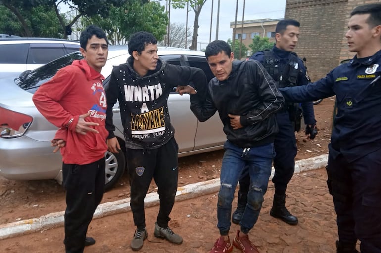 Efectivos policiales custodian a tres de los doce evadidos que fueron atrapados momentos después de la masiva fuga ocurrida en la Penitenciaría Regional de Misiones.
