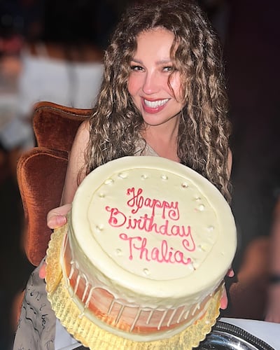 Thalía posando feliz con su torta de cumpleaños.
