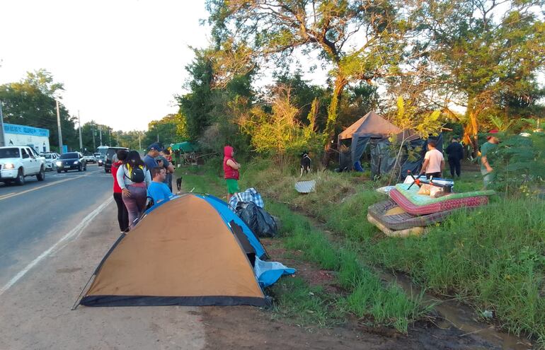 Los ocupantes con sus pertenencias sobre la vía pública, al costado de la propiedad supuestamente privada que está ubicada en Tarumandy, Luque.