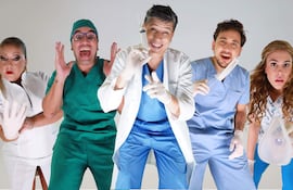 Cinco personas en ambiente divertido: dos mujeres y tres hombres, con uniformes médicos y expresiones cómicas, sosteniendo objetos y gesticulando.