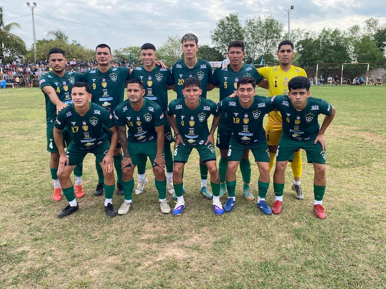 Jugadores del equipo de fútbol celebrando en la cancha, vistiendo camisetas verdes con detalles en blanco y azul, mientras los espectadores los aplauden.