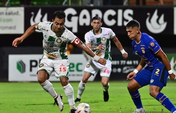 Ángel Cardozo Lucena, de Rubio Ñu, domina el esférico ante la marca de Paul Riveros, del Sportivo Luqueño.