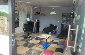 Interior de barbería con sillón negro y decoración en mármol; ambiente ordenado y bien iluminado.