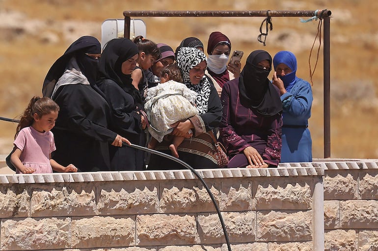 Personas observan cómo excavadoras de las fuerzas de seguridad israelíes demuelen una vivienda palestina —supuestamente construida sin permiso— en la localidad de Al-Dirat, al sur de Hebrón, en Cisjordania ocupada, el 14 de julio de 2026. Desde el inicio de la guerra en Gaza en octubre de 2023, la violencia se ha intensificado en Cisjordania.