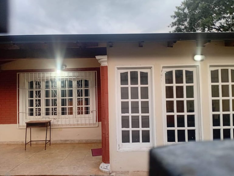 Edificio de ladrillo rojo con paredes blancas y mesa de metal frente a ventana con rejas.