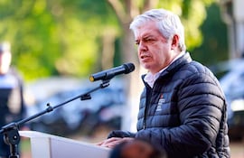 Enrique Riera en chaqueta negra habla en podio con micrófono ante una multitud en un evento al aire libre.
