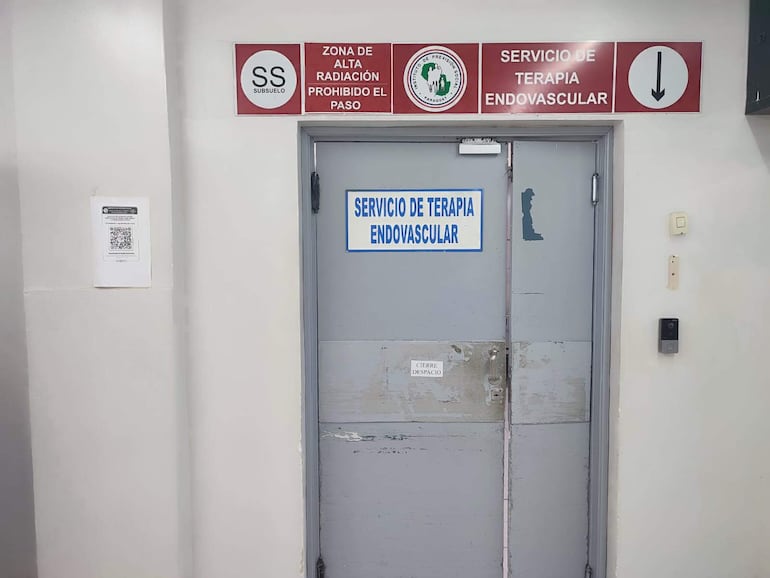 Puerta de acceso con letreros que indican servicio de terapia endovascular y advertencia de alta radiación, sin personas visibles.