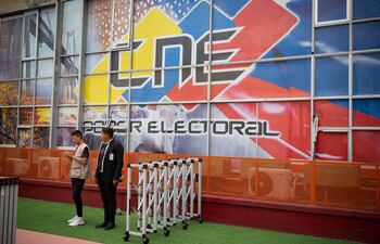 Personas vigilan un acceso a la sede del Consejo Nacional Electoral (CNE), el 17 de abril de 2024, en Caracas (Venezuela). A 100 días de las elecciones presidenciales en Venezuela, la oposición mayoritaria intenta escoger un candidato de coalición que se enfrente en las urnas a Nicolás Maduro, que buscará su tercer mandato, mientras sigue sin definirse la observación internacional para los comicios, en un país que ya vive una frenética campaña. EFE/ Rayner Peña R.