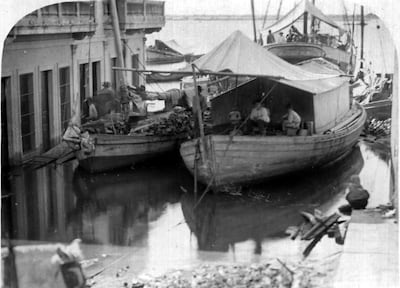 Barcos de madera amarrados en un puerto, con personas realizando actividades comerciales en un día soleado.