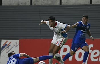 El defensor de Nacional, Rodrigo Melgarejo intenta filtrarse en medio de las marcas de Valentín Larralde y Luis Ortiz, del Sportivo Ameliano.
