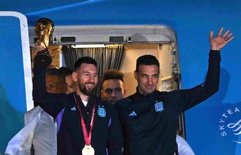 El capitán y delantero de Argentina, Lionel Messi (izq.), sostiene el trofeo de la Copa Mundial de la FIFA junto al entrenador de Argentina, Lionel Scaloni, al bajar del avión a su llegada al Aeropuerto Internacional de Ezeiza tras ganar el torneo de la Copa Mundial de Catar 2022 en Ezeiza, provincia de Buenos Aires, Argentina.