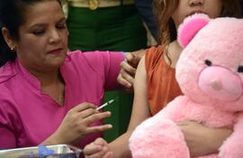 Una enfermera del hospital de niños Acosta Ñu aplica una dosis de vacuna contra el dengue a una niña.