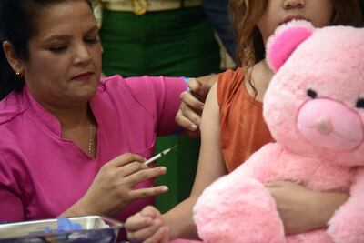 Una enfermera del hospital de niños Acosta Ñu aplica una dosis de vacuna contra el dengue a una niña. 