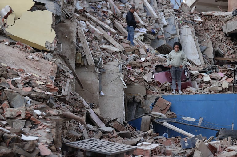 Residentes caminan entre los escombros de edificios derrumbados por los terremotos, en la localidad de Catia La Mar, en el estado costero de La Guaira (Venezuela), este jueves. 