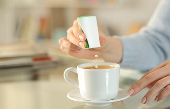 Una mujer endulza su café con sacarina.
