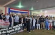 Grupo de médicos con batas en manifestación, sosteniendo pancartas, escuchando a un líder del movimiento.