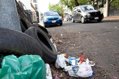 Calle en Asunción con neumáticos apilados y bolsas de basura, sin personas visibles.